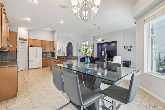 tiled dining area with lofted ceiling, sink, and ceiling fan with notable chandelier