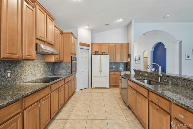 kitchen featuring lofted ceiling, sink, appliances with stainless steel finishes, and dark stone counters