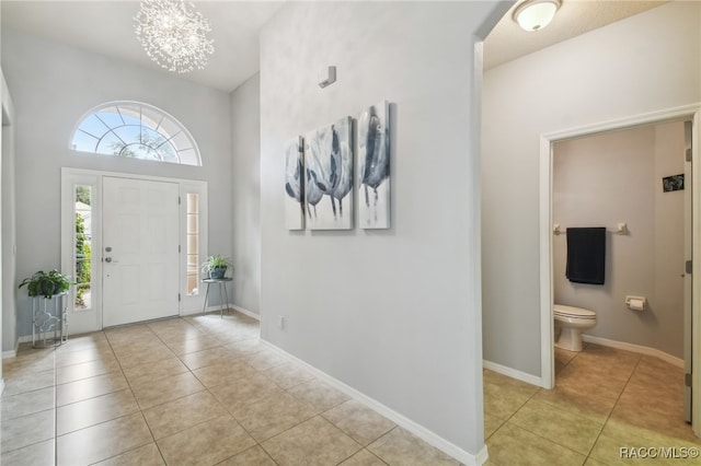 tiled foyer entrance with a towering ceiling and a chandelier