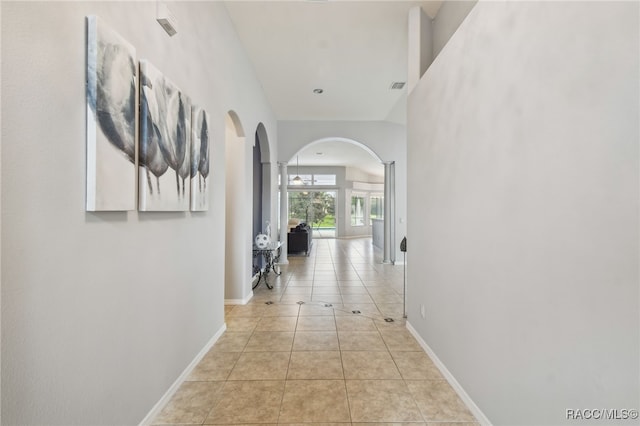 corridor with light tile patterned floors and ornate columns