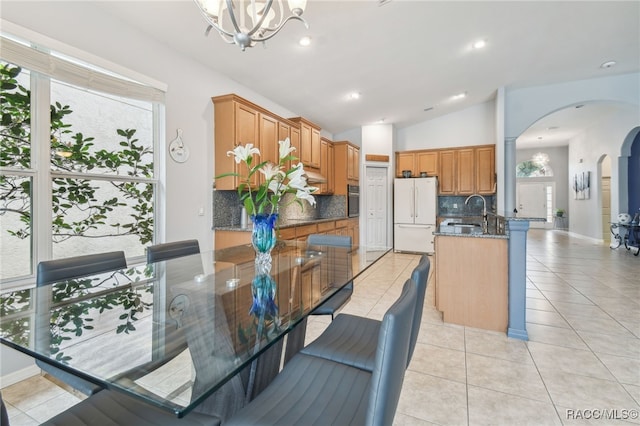 dining space with a chandelier, light tile patterned flooring, sink, and vaulted ceiling