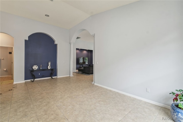 tiled empty room featuring lofted ceiling