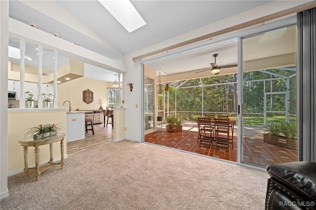 interior space featuring vaulted ceiling with skylight, dark carpet, and sink