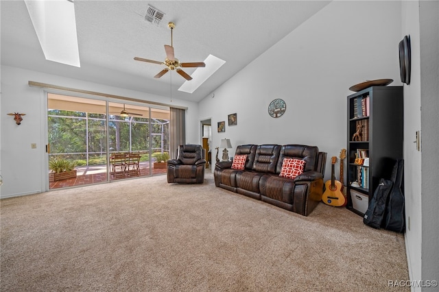 living room featuring a skylight, a textured ceiling, ceiling fan, high vaulted ceiling, and carpet floors