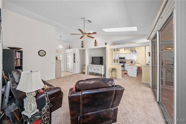 carpeted living room featuring sink, ceiling fan, and vaulted ceiling with skylight