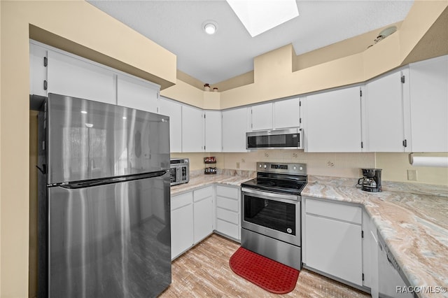 kitchen featuring appliances with stainless steel finishes, light hardwood / wood-style floors, white cabinetry, and a skylight