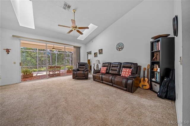 carpeted living room with a skylight, ceiling fan, and high vaulted ceiling