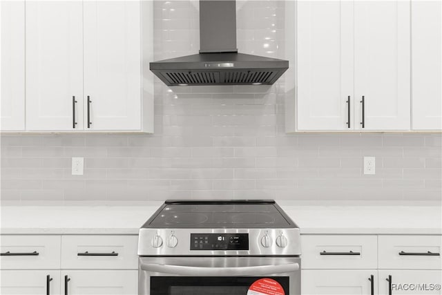 kitchen with white cabinets, stainless steel range oven, and wall chimney range hood