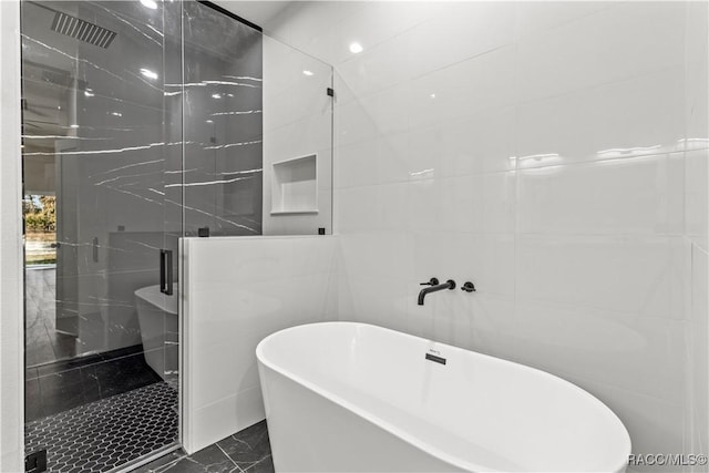 bathroom featuring tile walls and independent shower and bath