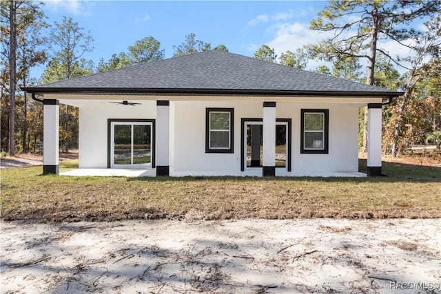 back of property featuring ceiling fan and a lawn