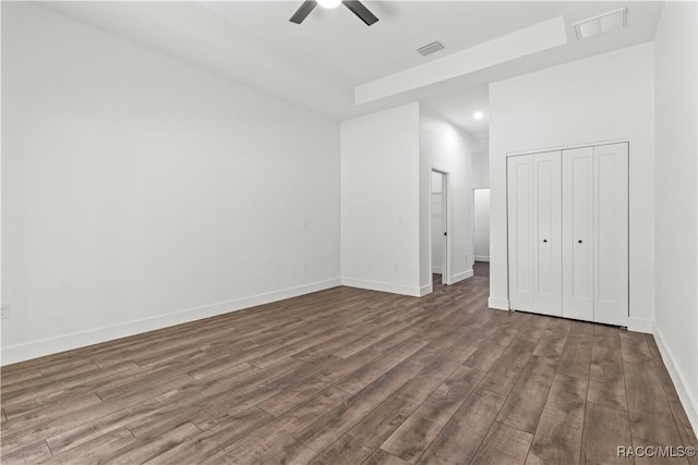 unfurnished bedroom with ceiling fan, wood-type flooring, a high ceiling, and a closet