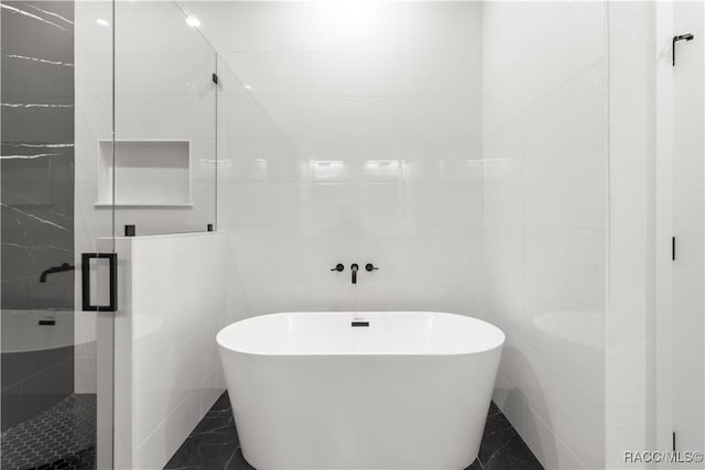 bathroom featuring shower with separate bathtub and tile walls