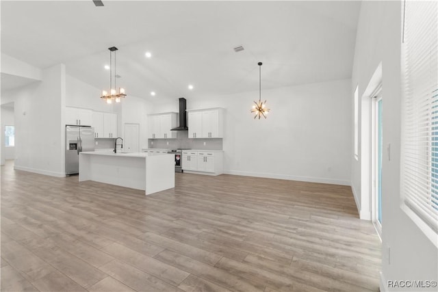 kitchen featuring a healthy amount of sunlight, light wood-type flooring, wall chimney range hood, and stainless steel appliances