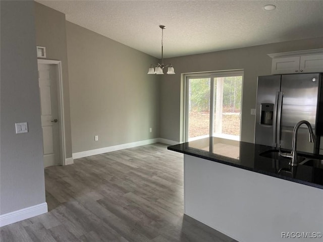 kitchen with stainless steel fridge, sink, pendant lighting, hardwood / wood-style floors, and white cabinetry