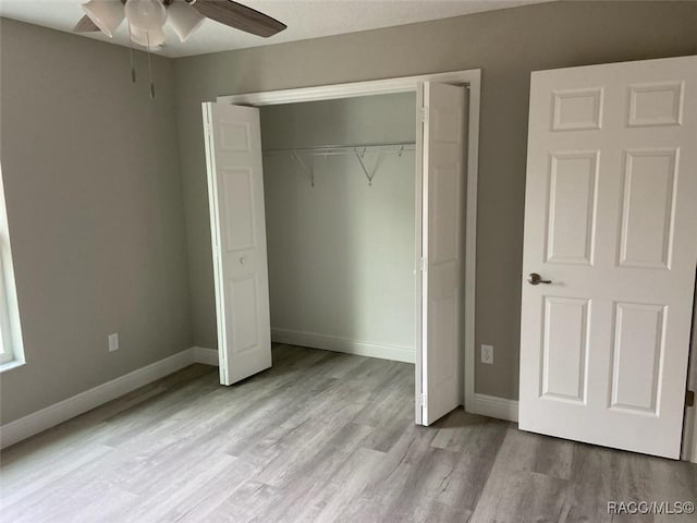 unfurnished bedroom with ceiling fan, light wood-type flooring, and a closet