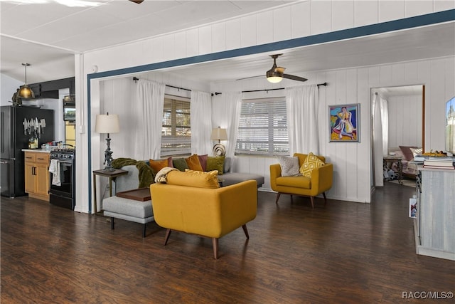 living room with ceiling fan, wood walls, and dark wood-type flooring