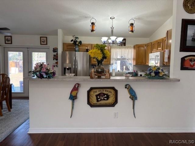 kitchen with a chandelier, stainless steel fridge with ice dispenser, dark hardwood / wood-style floors, kitchen peninsula, and pendant lighting