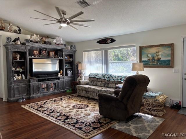 living room featuring vaulted ceiling, dark hardwood / wood-style floors, a textured ceiling, and ceiling fan