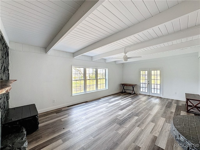 living area featuring french doors, a healthy amount of sunlight, beam ceiling, and wood finished floors