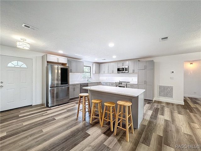 kitchen with appliances with stainless steel finishes, visible vents, gray cabinetry, and wood finished floors