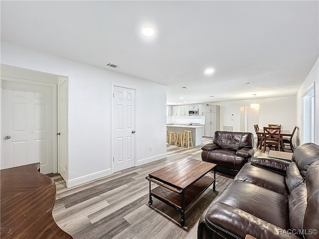 living room featuring light wood-style flooring, recessed lighting, visible vents, and baseboards