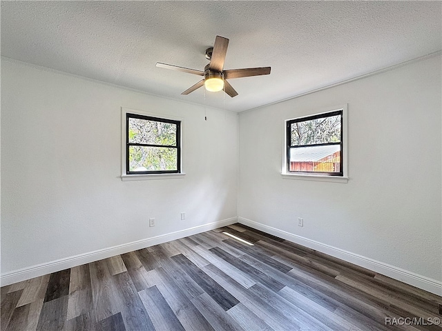 spare room featuring dark wood finished floors, a textured ceiling, and baseboards