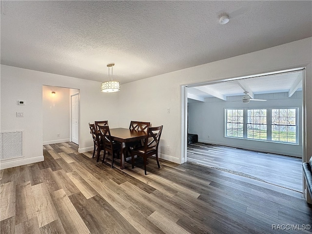 dining room with a textured ceiling, beam ceiling, wood finished floors, and visible vents