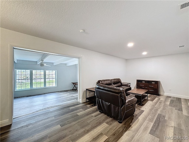 living room with beam ceiling, visible vents, and wood finished floors