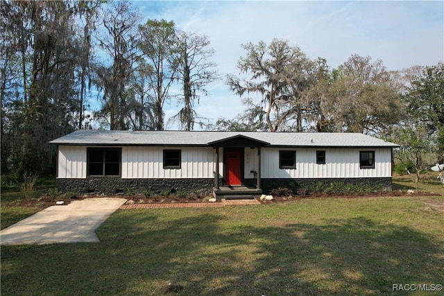 view of front facade with stone siding, a front lawn, and board and batten siding