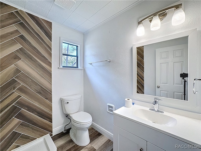 bathroom with baseboards, tiled shower, toilet, wood finished floors, and vanity