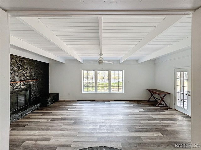 unfurnished living room with a fireplace, wood finished floors, and beam ceiling