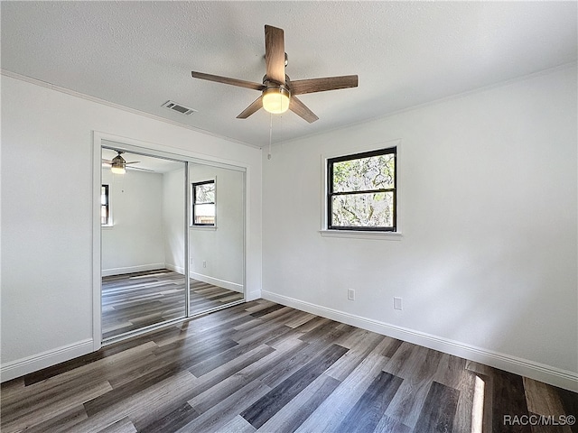 unfurnished bedroom featuring a closet, a textured ceiling, visible vents, and wood finished floors