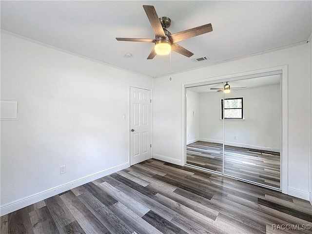 empty room featuring a ceiling fan, dark wood-style flooring, visible vents, and baseboards