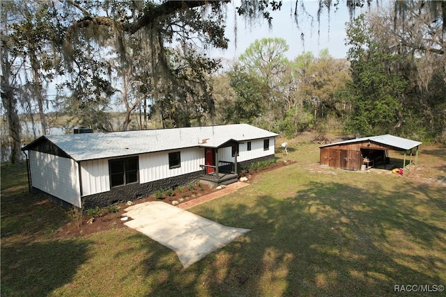 exterior space featuring driveway, an outbuilding, a carport, and a front yard