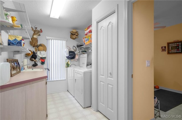 laundry room featuring laundry area, a textured ceiling, light floors, separate washer and dryer, and a sink