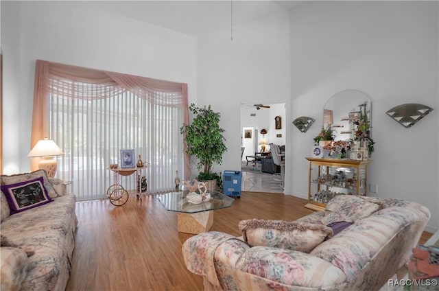 living area featuring ceiling fan, a high ceiling, and wood finished floors