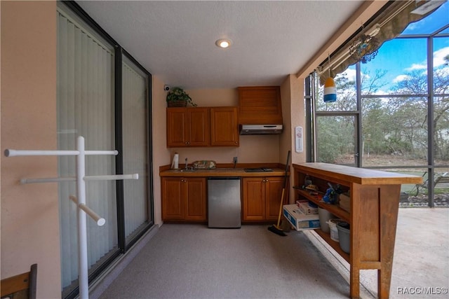 kitchen with fridge, under cabinet range hood, brown cabinets, and light colored carpet