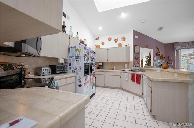 kitchen featuring white appliances, a toaster, visible vents, tile counters, and a peninsula