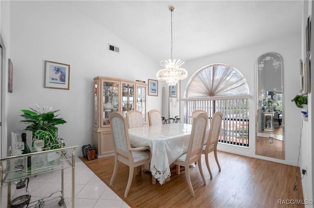 dining room featuring high vaulted ceiling, visible vents, light wood finished floors, and an inviting chandelier