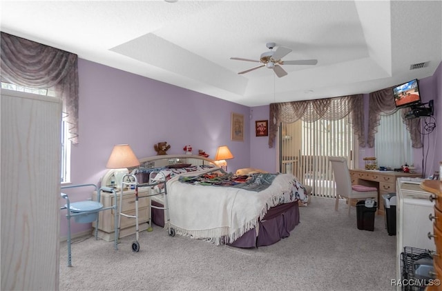 carpeted bedroom featuring a ceiling fan, access to outside, a raised ceiling, and visible vents