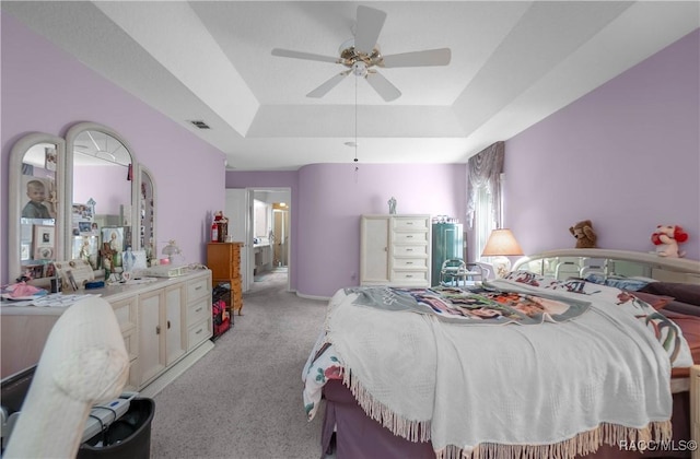 bedroom featuring ceiling fan, visible vents, a raised ceiling, and light colored carpet