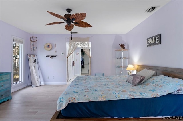 bedroom featuring multiple windows, ceiling fan, and light wood-type flooring