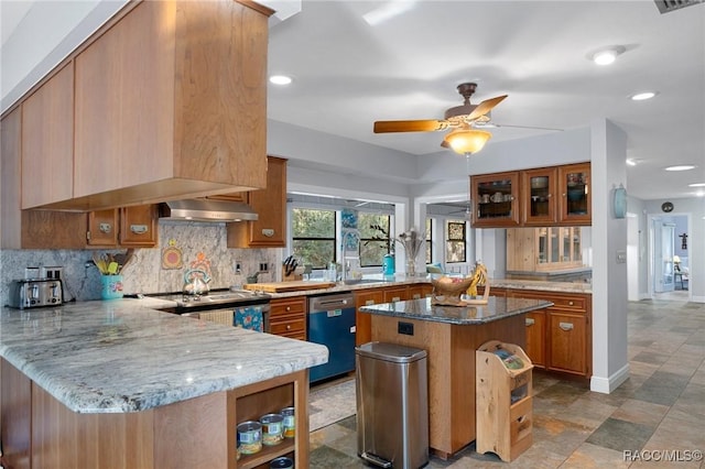 kitchen with light stone counters, a center island, kitchen peninsula, stainless steel appliances, and decorative backsplash