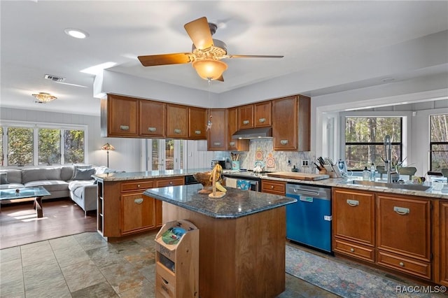 kitchen featuring a kitchen island, appliances with stainless steel finishes, dark stone countertops, and ceiling fan