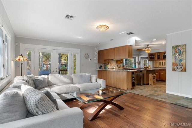 living room featuring light hardwood / wood-style flooring, ornamental molding, and french doors