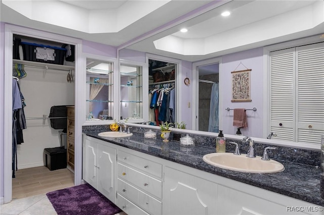 bathroom featuring a raised ceiling, vanity, and walk in shower