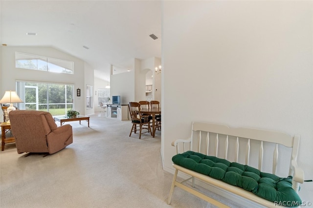 carpeted living room with high vaulted ceiling and an inviting chandelier