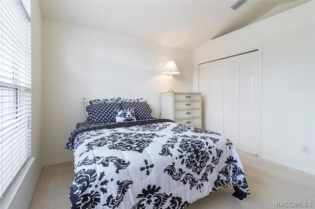 bedroom featuring light carpet, a closet, and lofted ceiling