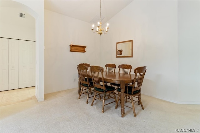 carpeted dining space with high vaulted ceiling and an inviting chandelier