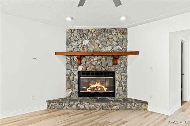 room details with ceiling fan, a fireplace, a textured ceiling, and hardwood / wood-style flooring